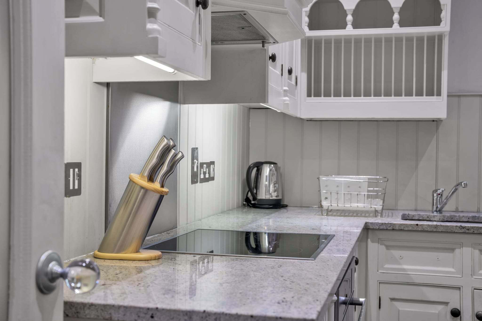 A kitchen with a glass-top island, stainless steel appliances, and white cabinetry.