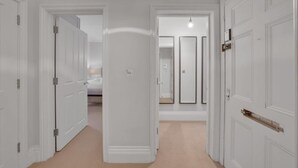 Een hal met witte deuren die naar slaapkamers leiden.