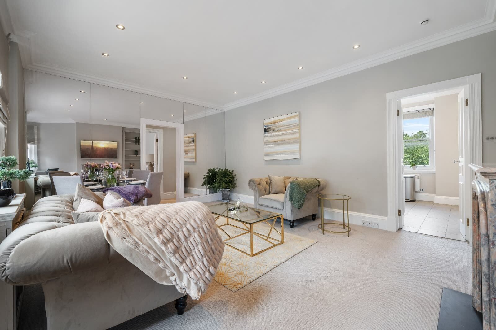 A spacious living room with a large sofa, a coffee table, and a dining area in the background.