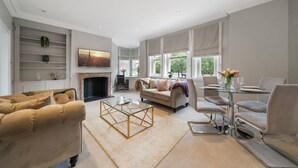 Ein geräumiges Wohnzimmer mit Kamin, einer Couch, einem Couchtisch und einem Essbereich mit Stühlen.