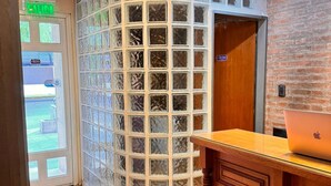A reception area with a wooden desk, a glass partition, and a door marked "SALIDA". - HOTEL CUESTA DEL VIENTO (San Juan)