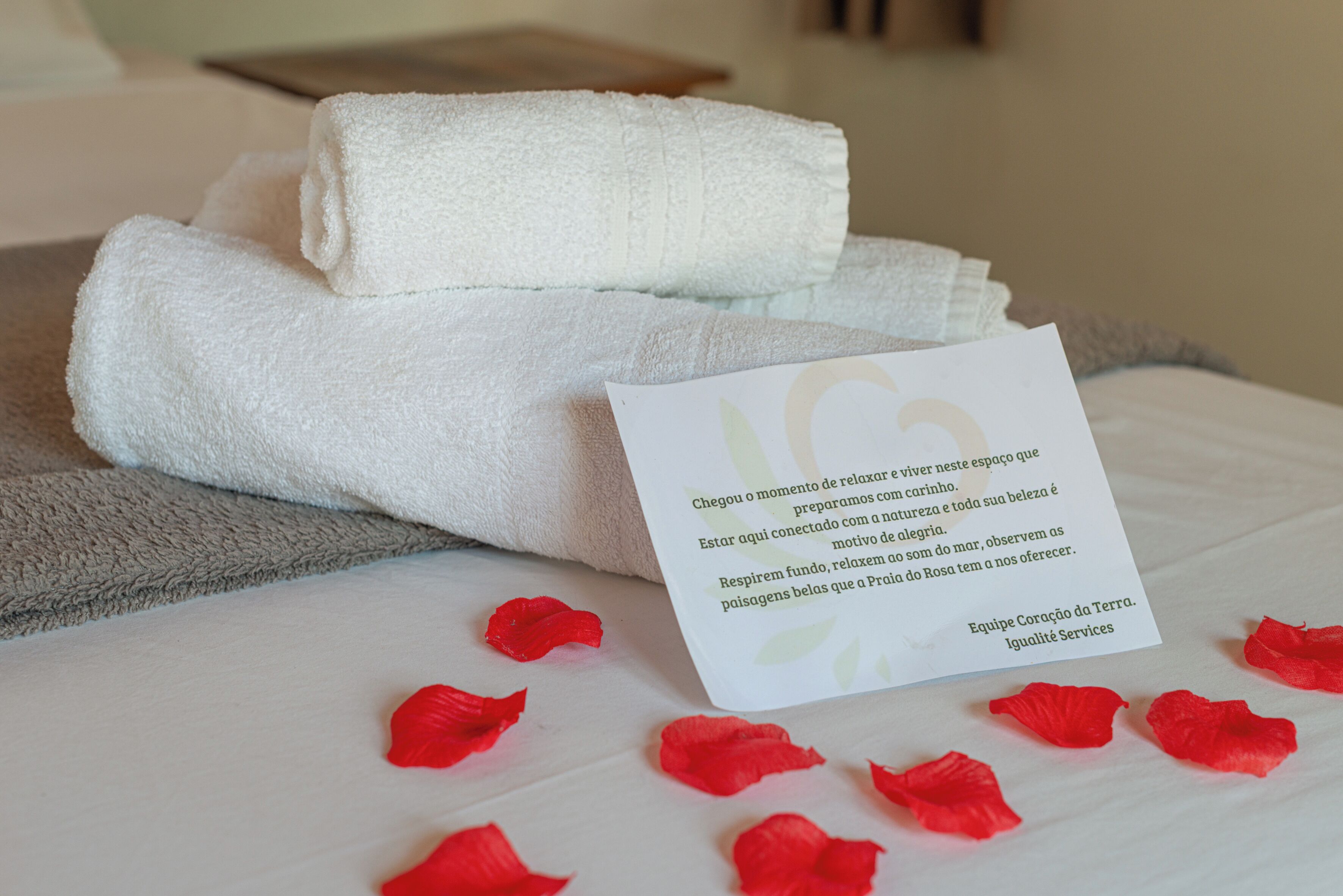 A neatly made bed with folded white towels and a card with text.