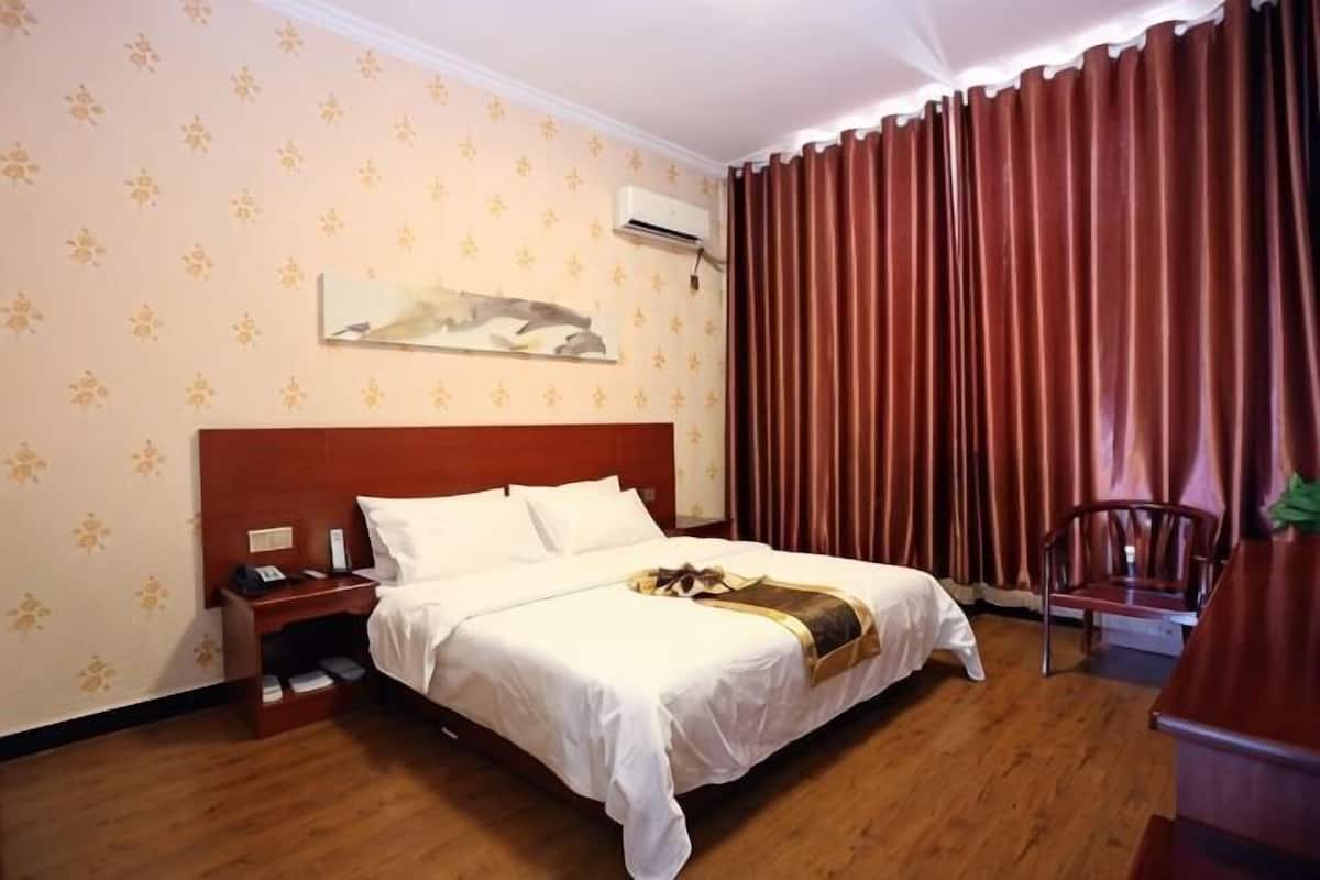 A hotel room with a wooden bed, a nightstand, a chair, and a desk.