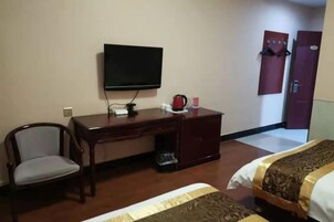 Una habitación de hotel con cama, escritorio con televisor, una silla y armario.