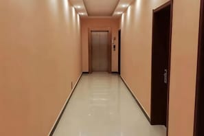 A corridor with a door at the end, a light switch on the wall, and a door handle on the right. - Bayun Hotel (Wuyuan Bus Station) (Wuyuan)