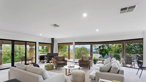 Un salón amplio con ventanas grandes, chimenea y muebles modernos.
