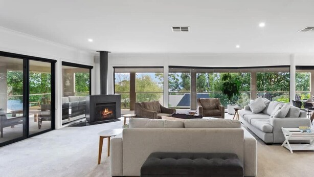 Una sala de estar amplia con chimenea, ventanas grandes y un balcón.