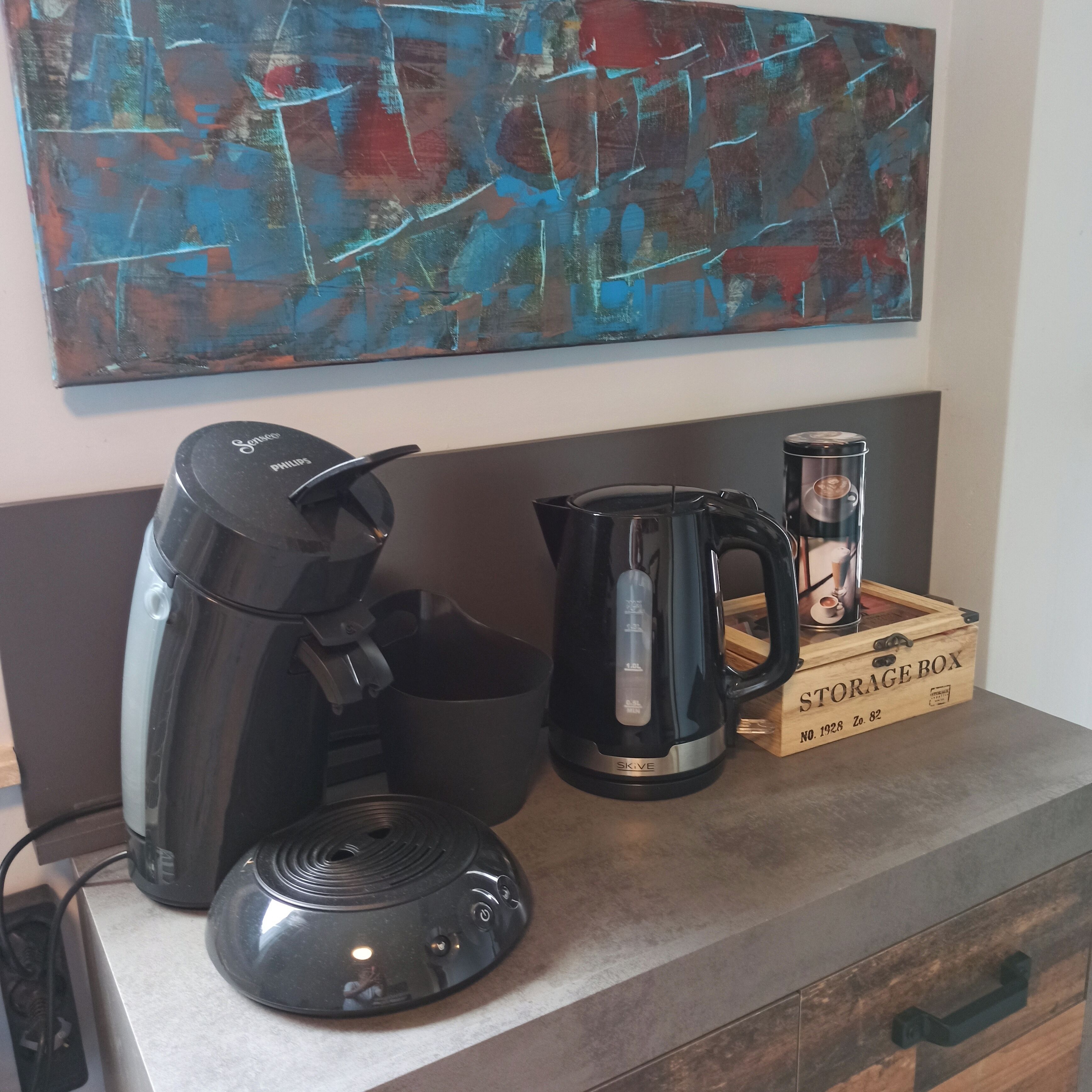 Eine Küchenarbeitsplatte mit einer Kaffeemaschine, einem Wasserkocher und einer Aufbewahrungsbox.