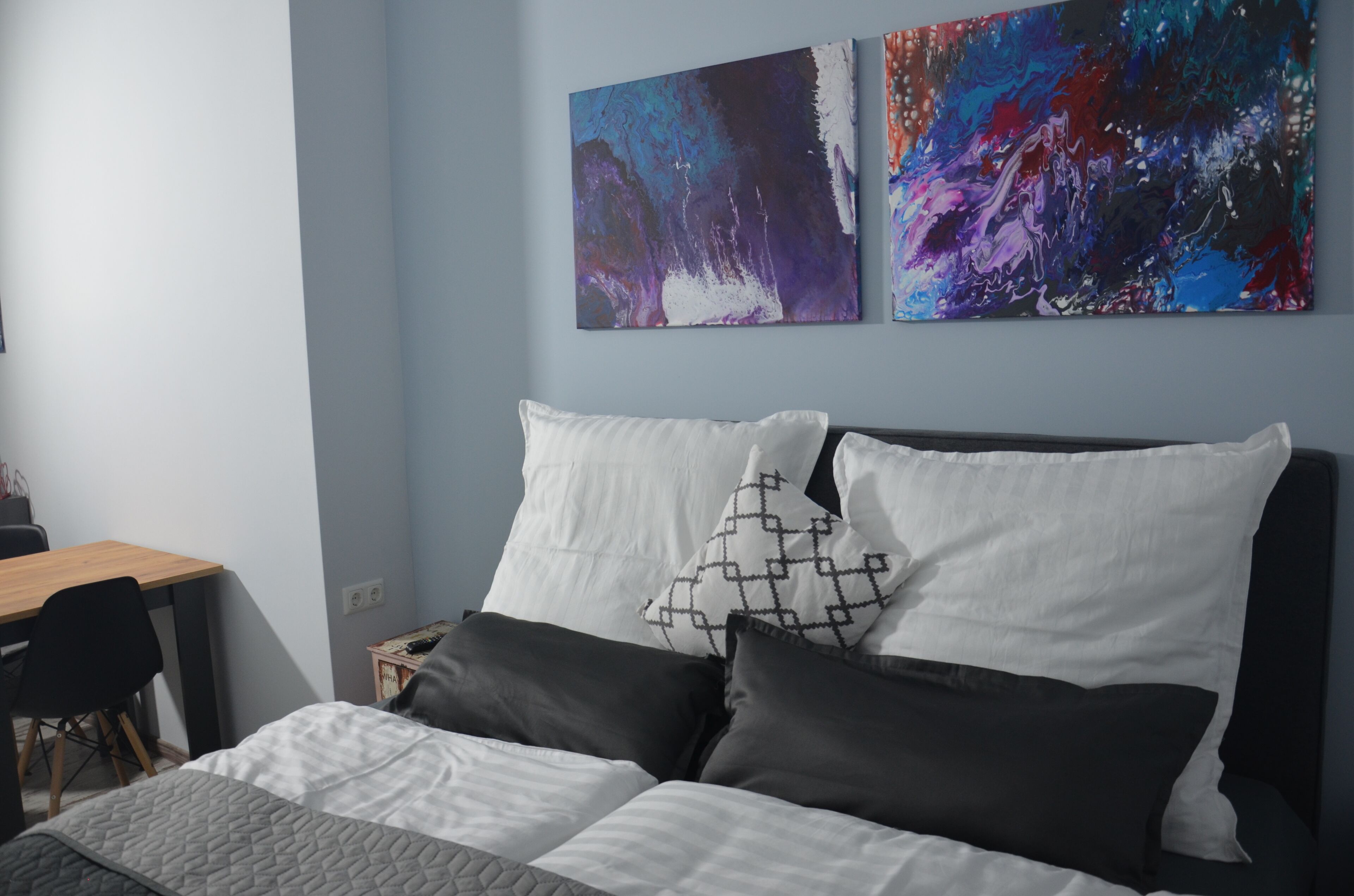 A bedroom with a bed, two pillows, a desk, and a chair.