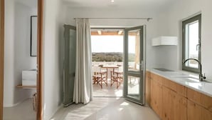 Une cuisine moderne avec des meubles en bois, un plan de travail blanc et une vue sur un espace de restauration extérieur.