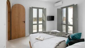 Une chambre à coucher avec un lit, une porte ouverte et un téléviseur fixé au mur.