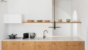 Une cuisine moderne avec des meubles blancs, une bouilloire en acier inoxydable, une casserole noire et un seul robinet.