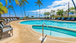 Une piscine avec des chaises longues et des palmiers.