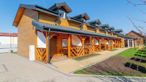 Een rij houten blokhutten met aanleunplekken, een verhard pad en een aangelegde tuin.