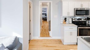 A modern kitchen with white cabinets, a microwave, a stove, and a countertop. - 86B  King Bed - Downtown - Walk everywhere (Charlottetown)