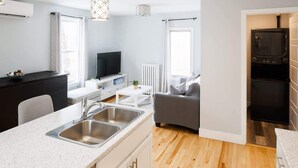 A modern kitchen with a built-in oven and a dining area with a white table and chairs. - 86B  King Bed - Downtown - Walk everywhere (Charlottetown)