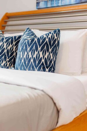 A bed with white bedding and two blue patterned pillows. - 86B  King Bed - Downtown - Walk everywhere (Charlottetown)