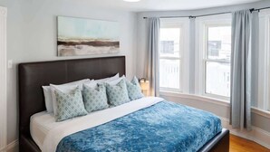 A bedroom with a large bed, a headboard, and a window with curtains. - 86B  King Bed - Downtown - Walk everywhere (Charlottetown)