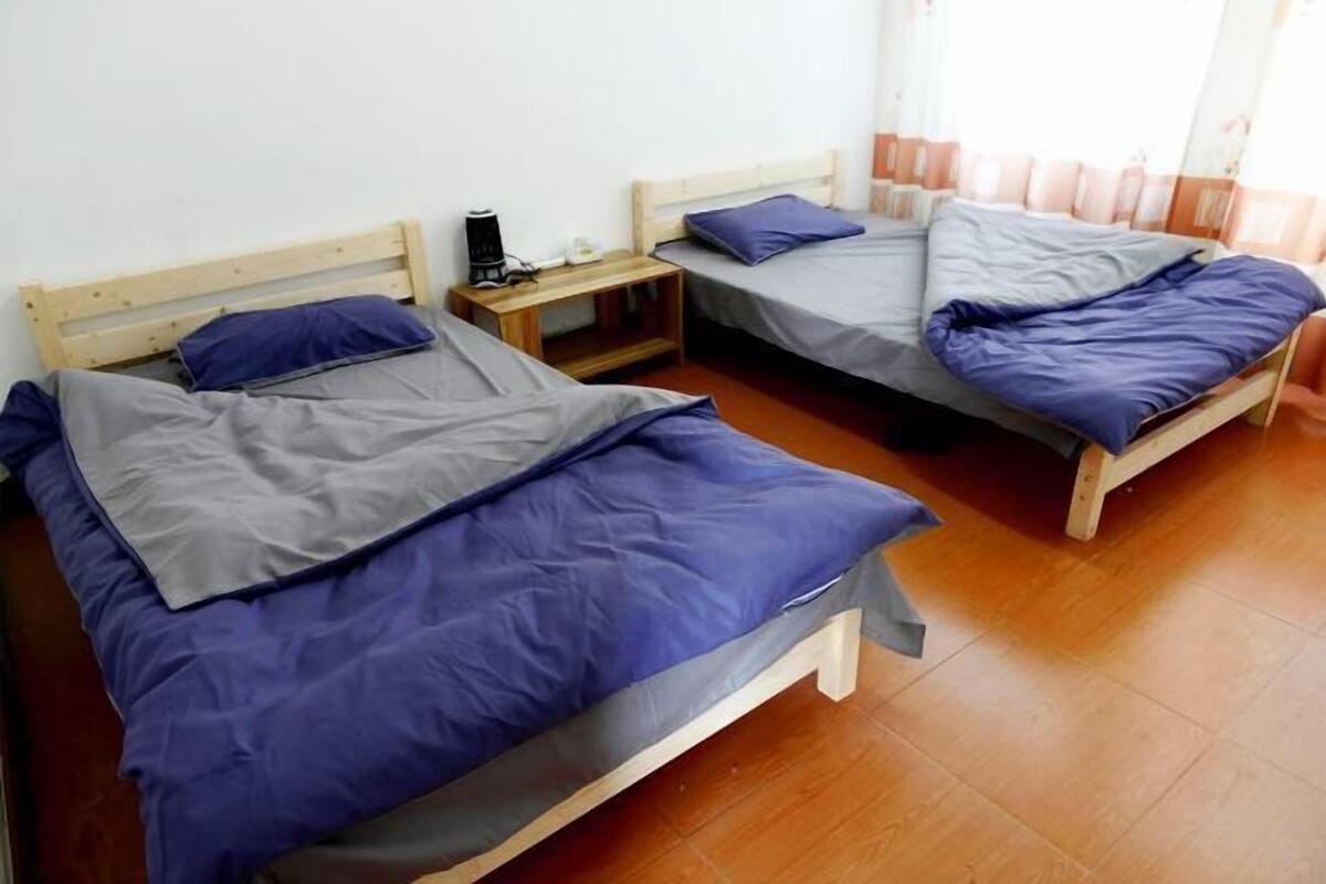 Habitació amb dos llits individuals, cadascun amb capçalera de fusta i una petita taula de nit.
