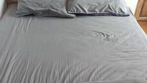 A bed with a grey sheet and two pillows. - Wuyishan Blue Sky Youth Hostel (Wuyishan)