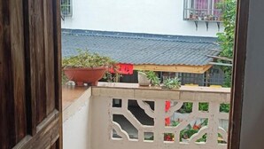 A balcony with a view of a traditional tiled roof, potted plants, and a wooden structure. - Wuyishan Blue Sky Youth Hostel (Wuyishan)