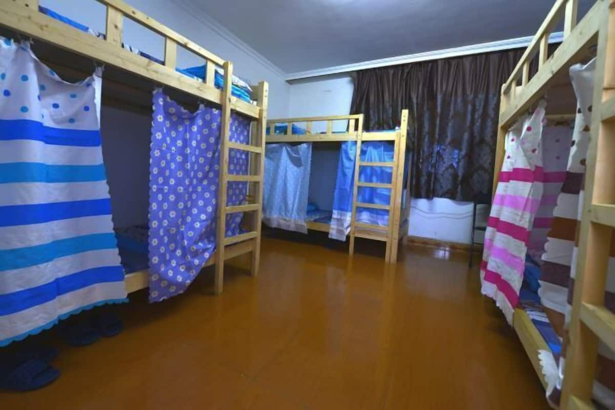 Habitació amb llits superposats, sòl de fusta i cortines.