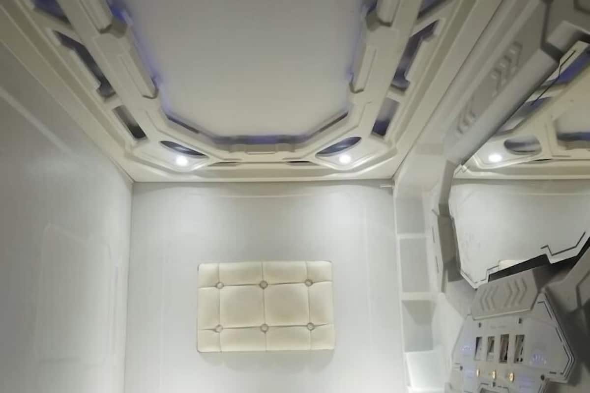 Habitació amb sostre blanc, il·luminació empotrada i un panell fixat al mur central.