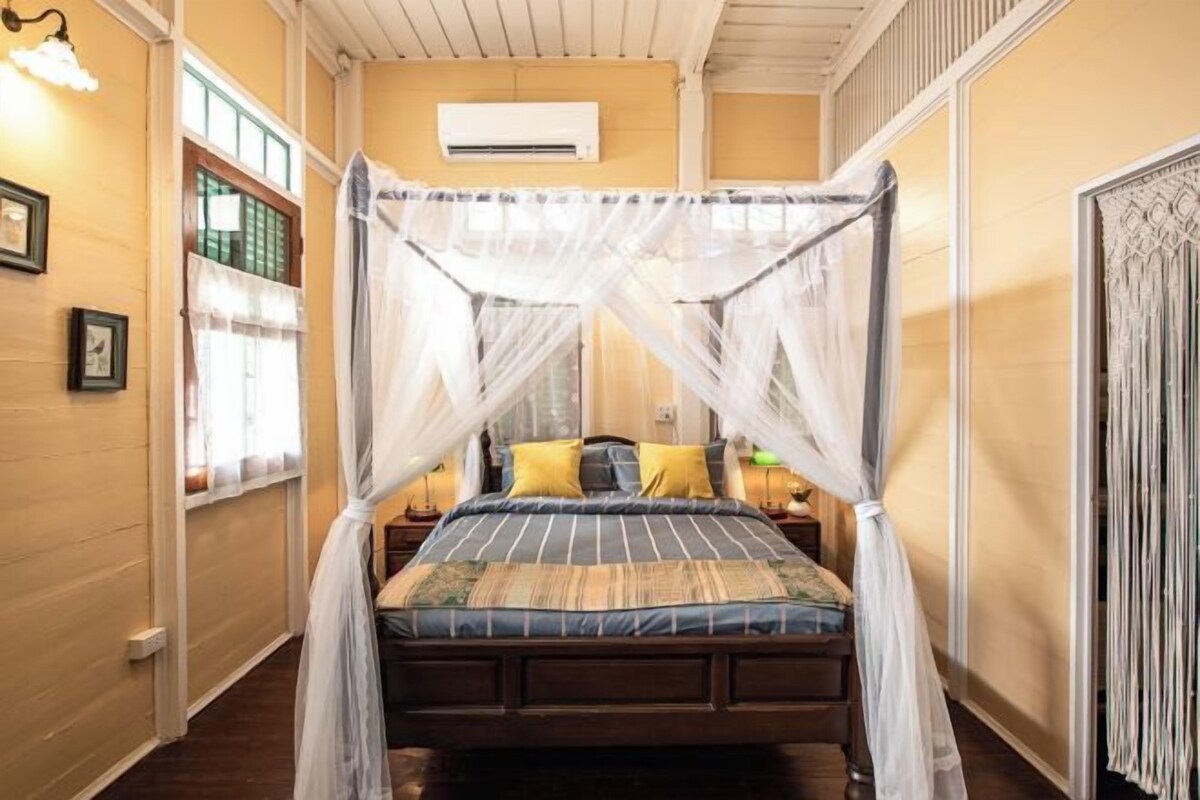 Een bed met hemelbed, een nachtkastje en een wandairconditioner.