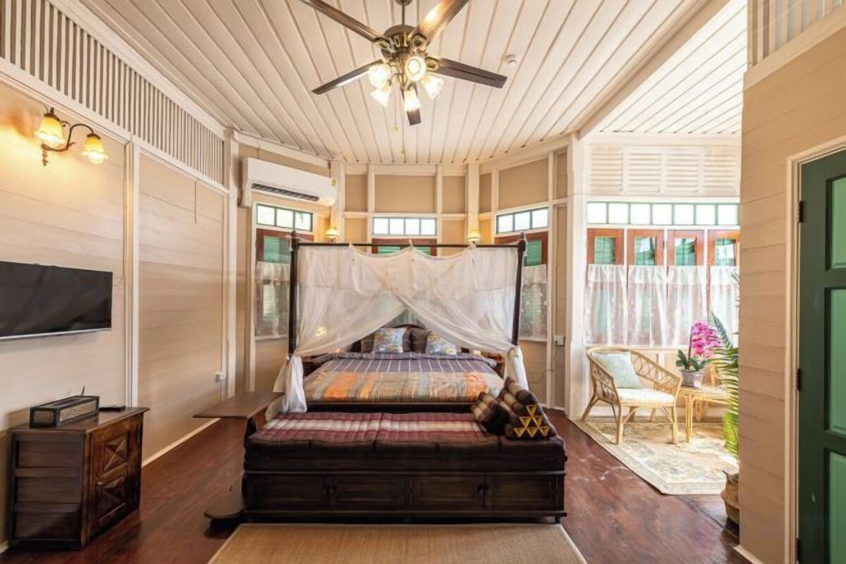 Une chambre à coucher avec un lit à baldaquin, un ventilateur de plafond et une vue sur l’extérieur.
