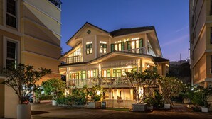 Un hôtel à plusieurs étages doté d’un balcon au deuxième étage, d’une entrée couverte et d’une façade bien éclairée.