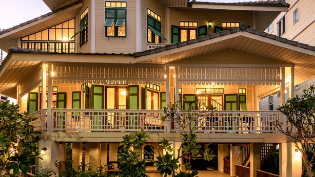 Un hôtel à plusieurs étages doté d’un balcon au deuxième étage, d’une entrée couverte et d’un jardin paysager à l’avant.