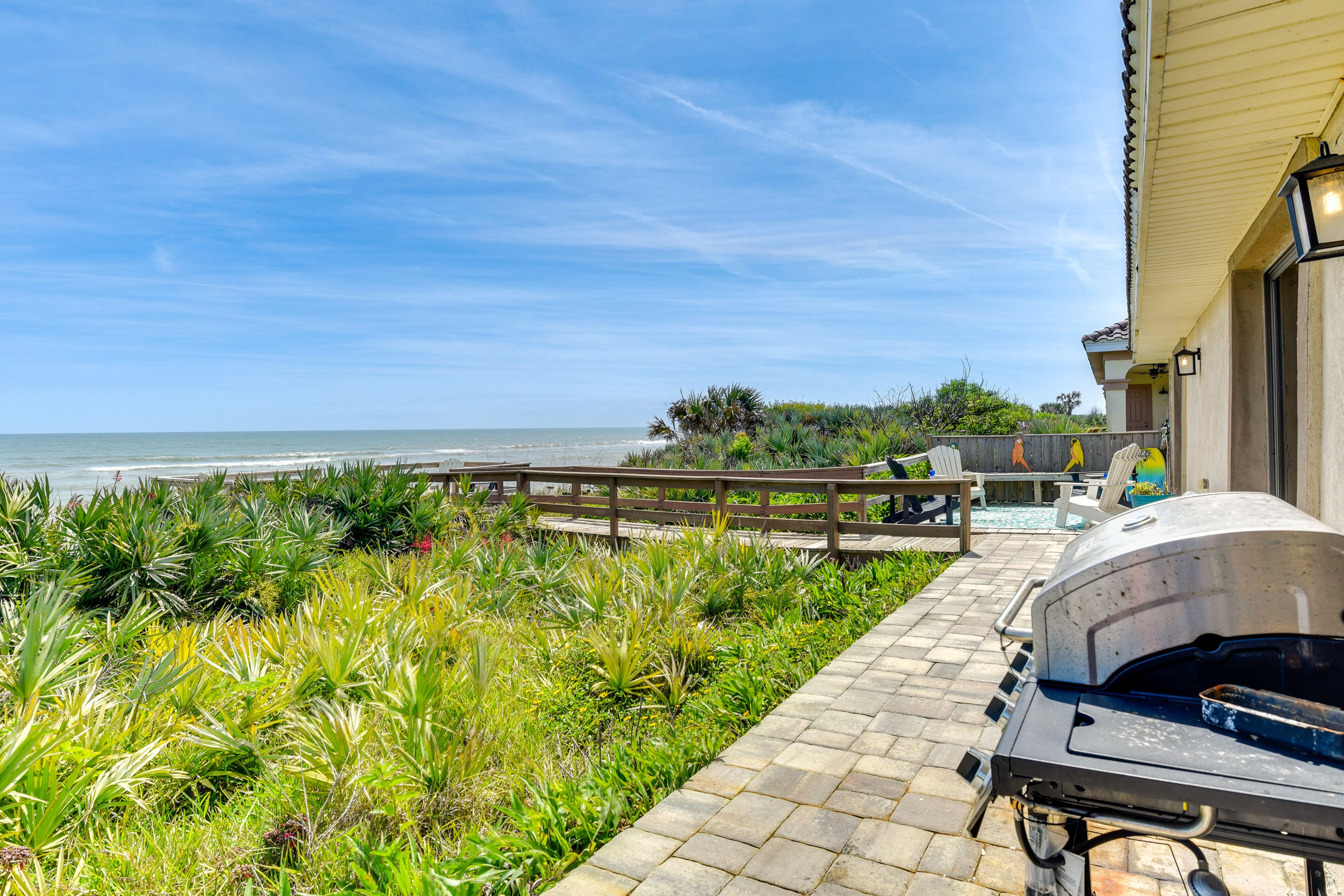 Un patio con una parrilla, una terraza de madera y vista al océano.