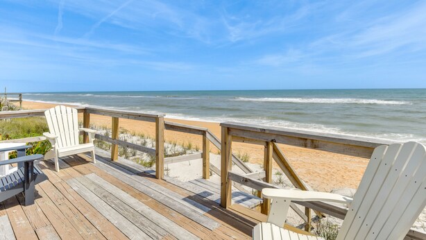 A wooden deck with white Adirondack chairs overlooking a sandy beach and ocean. - Oceanfront Flagler Beach Home w/ Decks & Gas Grill (Flagler Beach)