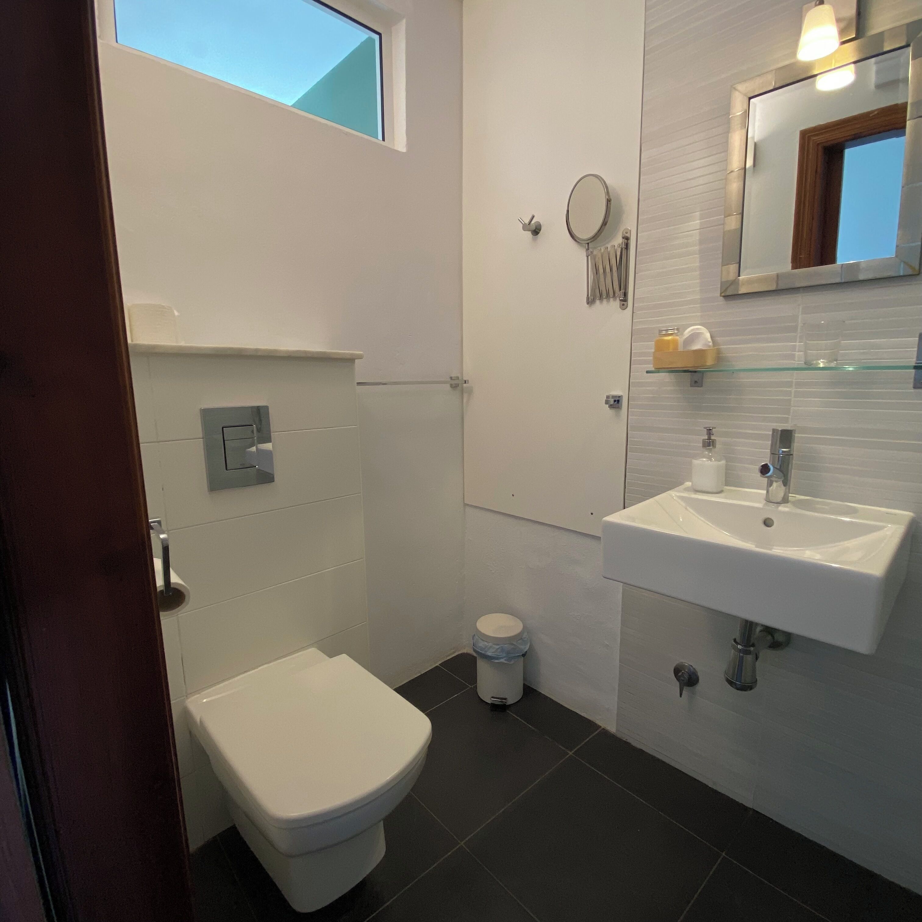 Un bagno moderno con il water, un lavandino e una piccola finestra.