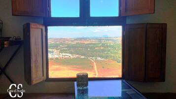 A room with a large window offering a view of a rural landscape.