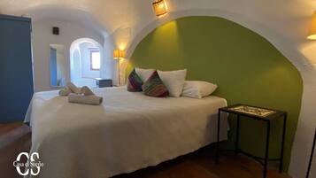 Un dormitorio con cama, almohadas, mesita de noche y lámpara.