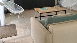 Una sala de estar moderna con sofá, mesa de centro, televisor y ventilador.