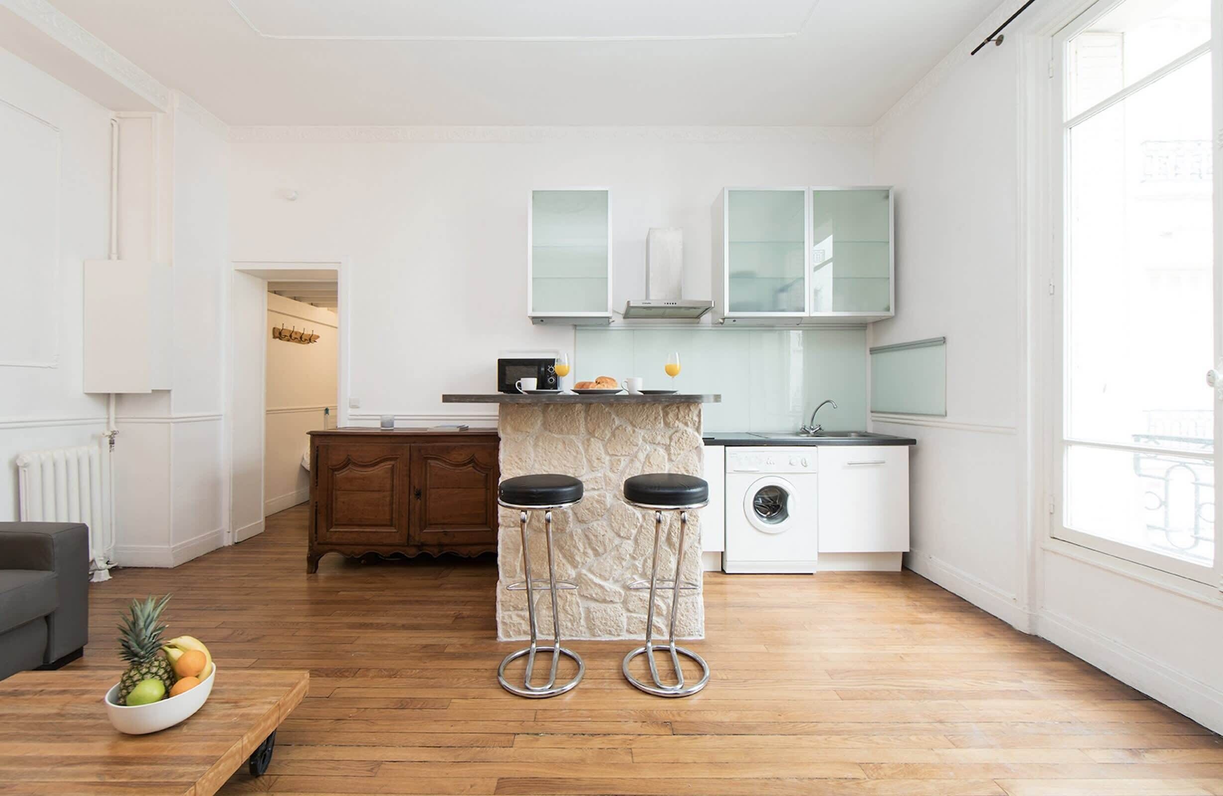 Een moderne keuken met een stenen kookeiland, barkrukken en een wasmachine.