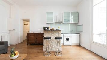 Een moderne keuken met een stenen kookeiland, barkrukken en een wasmachine.