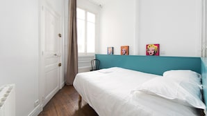 A bedroom with a bed, a window with curtains, and two framed pictures on the wall. - Charming 1BR Near Le Marais - the Heart of Paris (Paris)