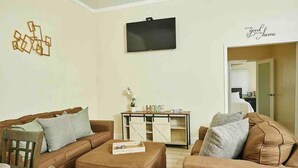 A living room with two sofas, a coffee table, and a TV on the wall. - Delva’s Place-Gated 3 bedroom - Pet Friendly (Freeport)