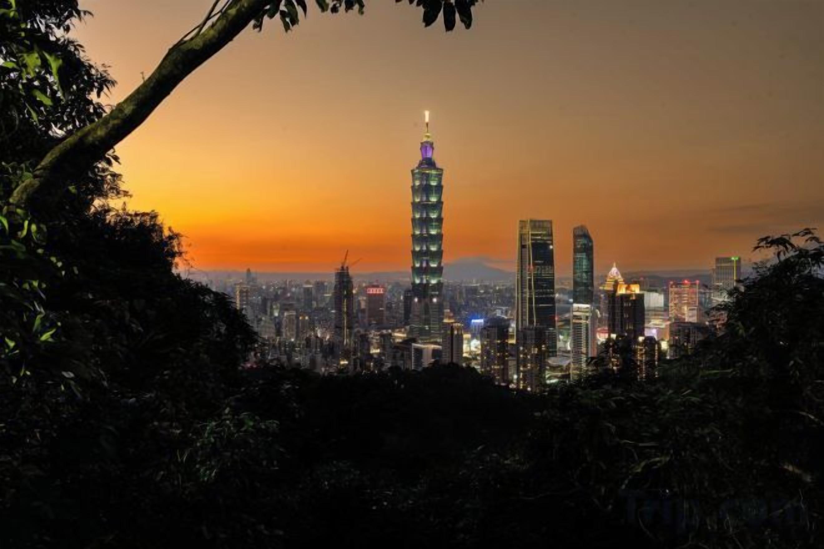 Paisagem urbana com um arranha-céu imponente, edifícios urbanos densos e um pôr do sol.