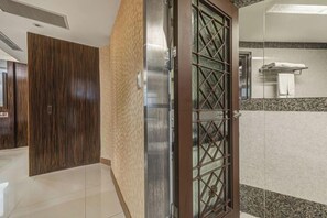 A hotel lobby with a wooden door, a tiled floor, and a mirror reflecting a towel rack. - Guide Hotel-Xinyi Branch（Ex HolyPro Hotel） (Taipei)