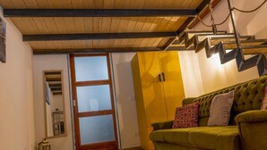A living room with a green sofa, wooden ceiling beams, and a yellow cabinet.