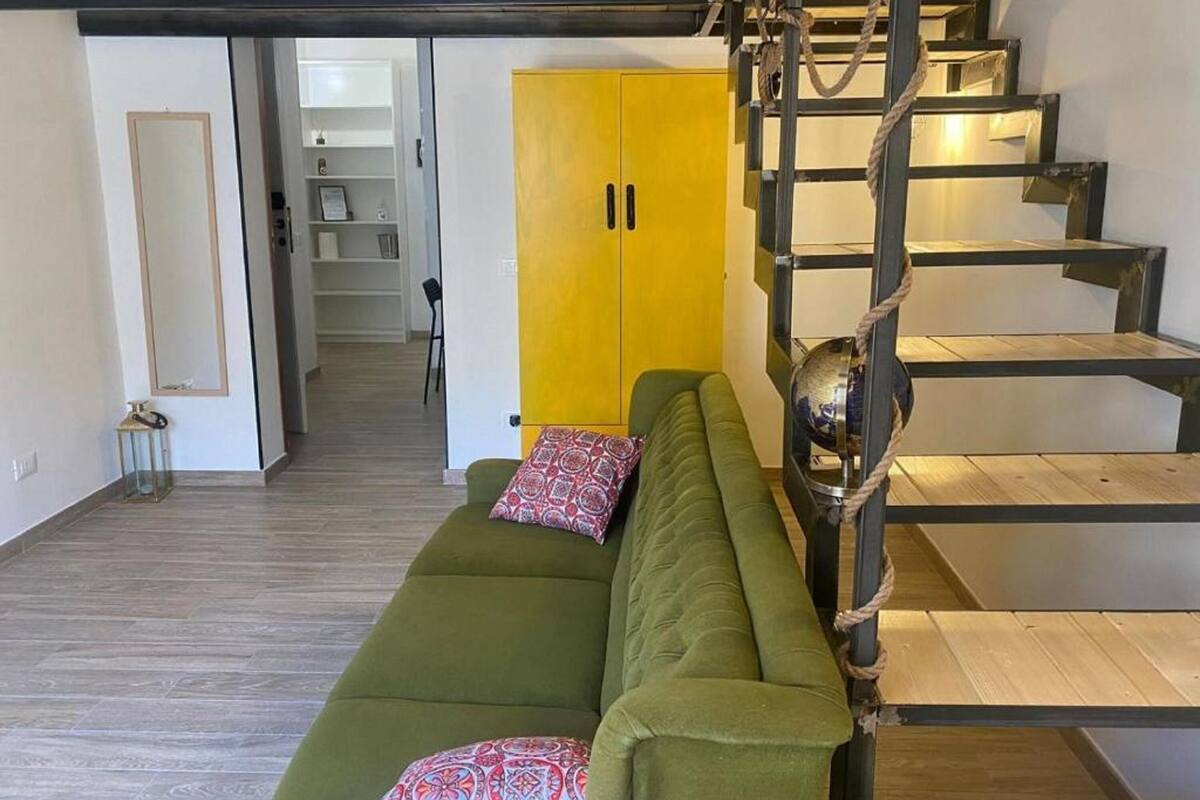 A modern living space with a green sofa, a yellow cabinet, and a wooden staircase.