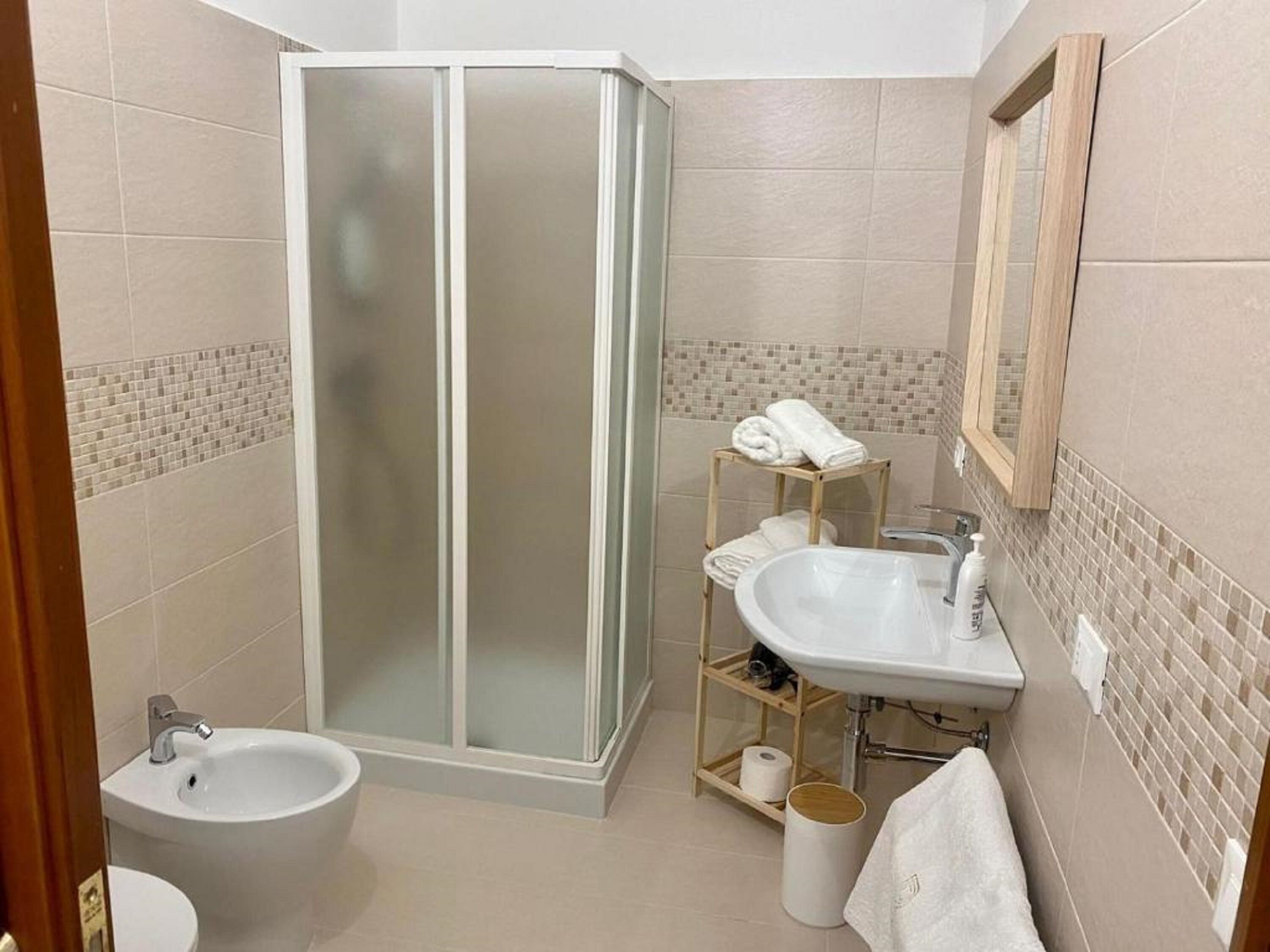 Un baño con ducha de vidrio, lavamanos y retrete.