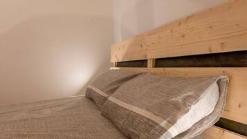 Ein Bett mit einem Holz-Kopfstück und einem grau gestreiften Kopfkissen.