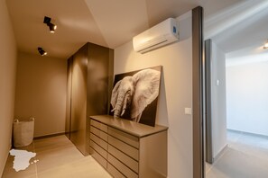 A modern interior with a wall-mounted air conditioning unit, a large framed artwork, and a minimalist storage unit.