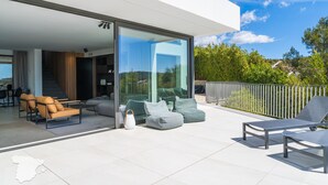 Un espace de vie extérieur moderne, doté d’un mur de verre, de sièges et offrant une vue sur le paysage environnant.