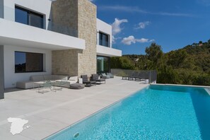 A modern outdoor pool area with a stone wall, seating, and a clear view of the surrounding landscape.